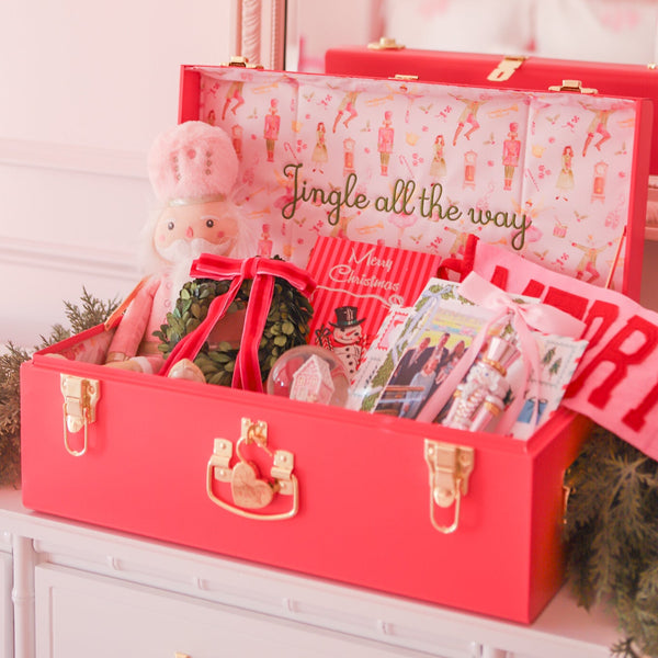 Hot Pink Holiday Trunk with festive items on a white surface, decorated with greenery and a wreath.